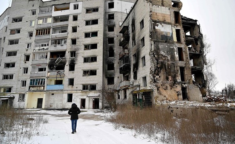 أوكرانية تمر أمام مبنى مدمر في بلدة بورودينكا 	(أ.ف.پ)