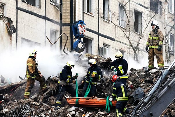عمال الإنقاذ ينتشلون جثة من تحت أنقاض مبنى دمره صاروخ روسي في دنيبرو (رويترز)