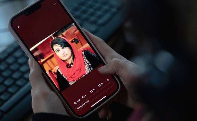 امرأة تنظر إلى صورة النائبة الأفغانية السابقة مرسال نبي زاده على هاتفها المحمول (أ.ف.پ)
