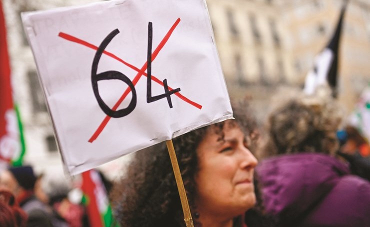 متظاهرة تحمل لافتة كتب عليها رقم 64 مشطوبا احتجاجا على رفع سن التقاعد	 (رويترز)