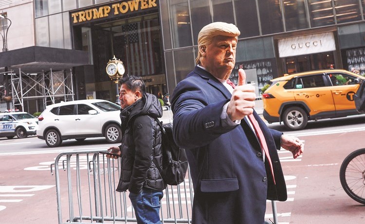 شخص يرتدي قناعا على شكل الرئيس الأميركي السابق دونالد ترامب خارج برج ترامب	(رويترز)