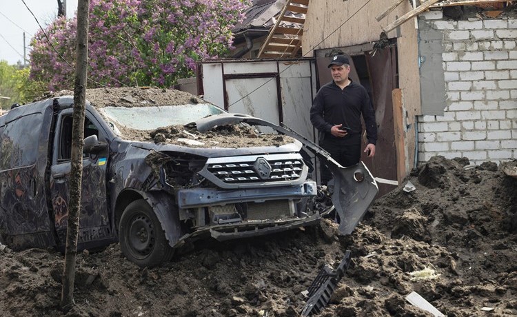 رجل يقف بجوار سيارة دمرتها ضربة صاروخية روسية في قرية تشيركوني (رويترز)