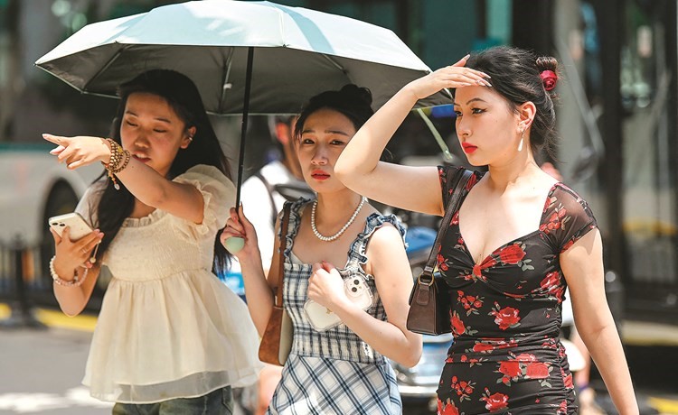سيدات يستخدمن مظلة للاحتماء من الشمس في شنغهاي	 (أ.ف.پ)