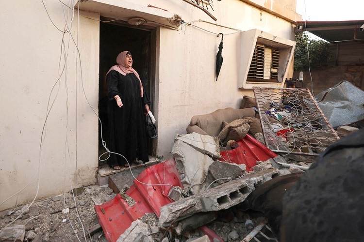 سيدة فلسطينية تتفقد بقايا منزل أحد جيرانها بعد أن هدمته قوات الاحتلال في نابلس (أ.ف.پ)
