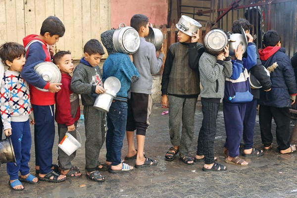 أطفال فلسطينيون ينتظرون للحصول على الطعام من مطبخ خيري في رفح (رويترز)