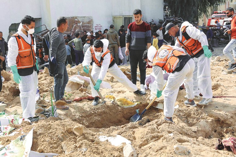 الدفاع المدني الفلسطيني يستخرج جثثا مدفونة في أرض مستشفى الشفاء بمدينة غزة 					 (أ.ف.پ)