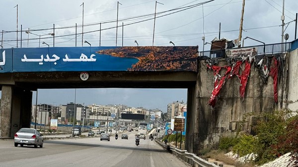 حريق قرب لافتة تحمل شعار «عهد جديد» على طريق مطار بيروت بالضاحية الجنوبية (محمود الطويل)