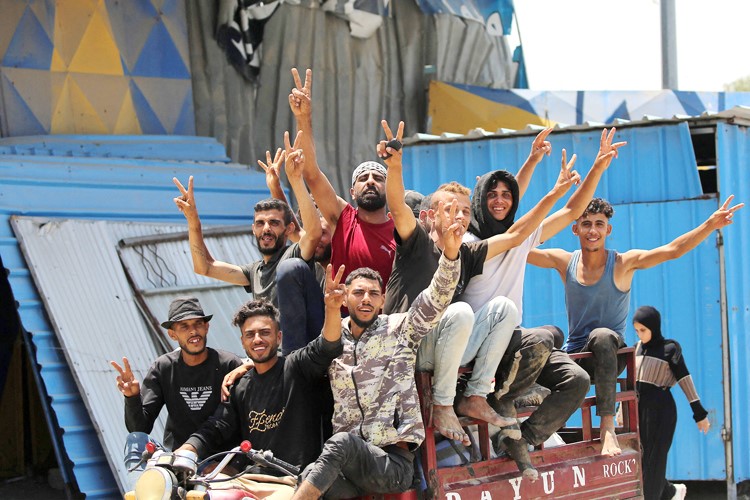 فلسطينيون يشيرون بعلامة النصر في دير البلح وسط قطاع غزة 	(أ.ف.پ)