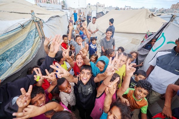  أطفال غزة يحتفلون بين الخيام البالية ابتهاجا بوقف النار في النصيرات وسط القطاع وفي الإطار الرئيس الاميركي دونالد ترامب لدى تلقيه ملاحظة تعلمه بموافقة حماس واسرائيل على توقيع الاتفاق				(أ.ف.ب)