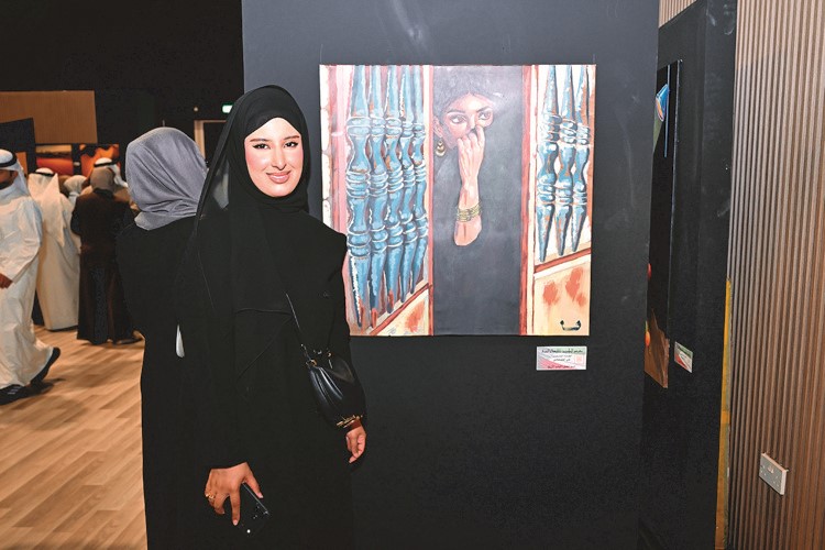 الفنانة التشكيلية م.في القحطاني مع لوحتها في المعرض