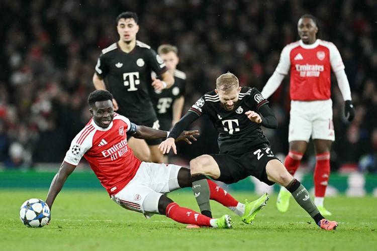 لاعب بايرن ميونيخ كونراد لايمر يعرقل مهاجم أرسنال بوكايو ساكا (أ.ف.پ)
