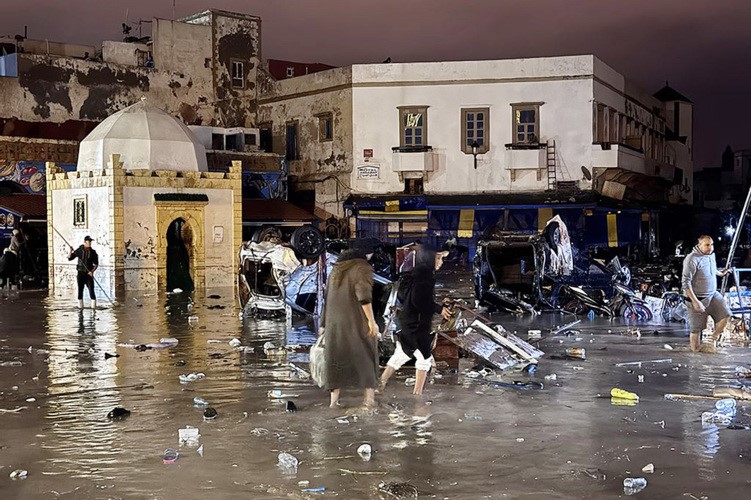 مغاربة يخوضون في مياه الفيضانات التي ضربت مدينة آسفي المغربية (أ.ف.ب)
