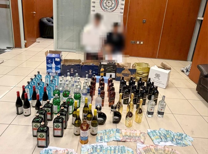 المتهمان وأمامهما الخمور المضبوطة وحصيلة البيع