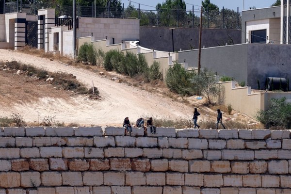 مستوطنون إسرائليون تجمعوا أمام منازل فلسطينية في قرية قصرة جنوب نابلس (أ.ف.ب)